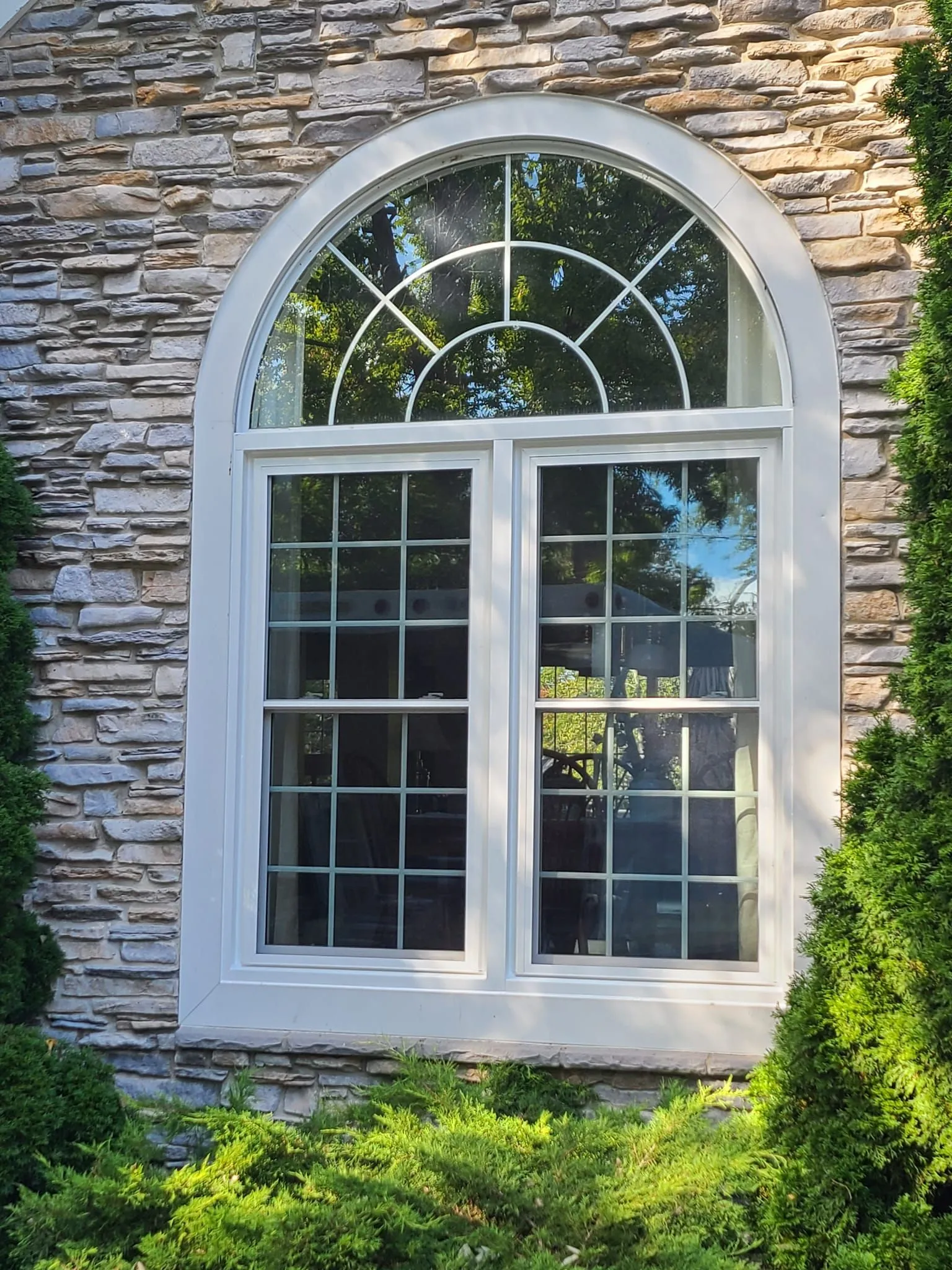 Arched replacement window installed in a stone home exterior